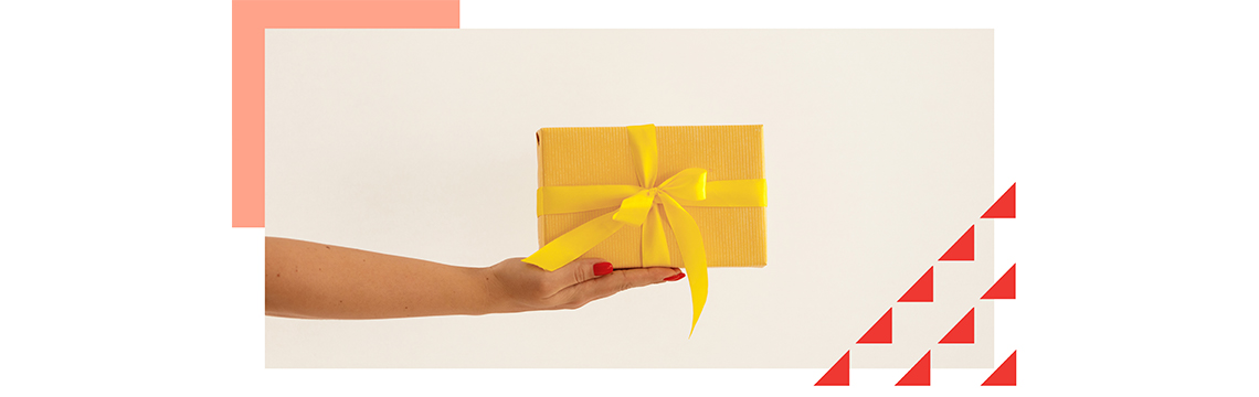 female hand holding small yellow gift box with a bow